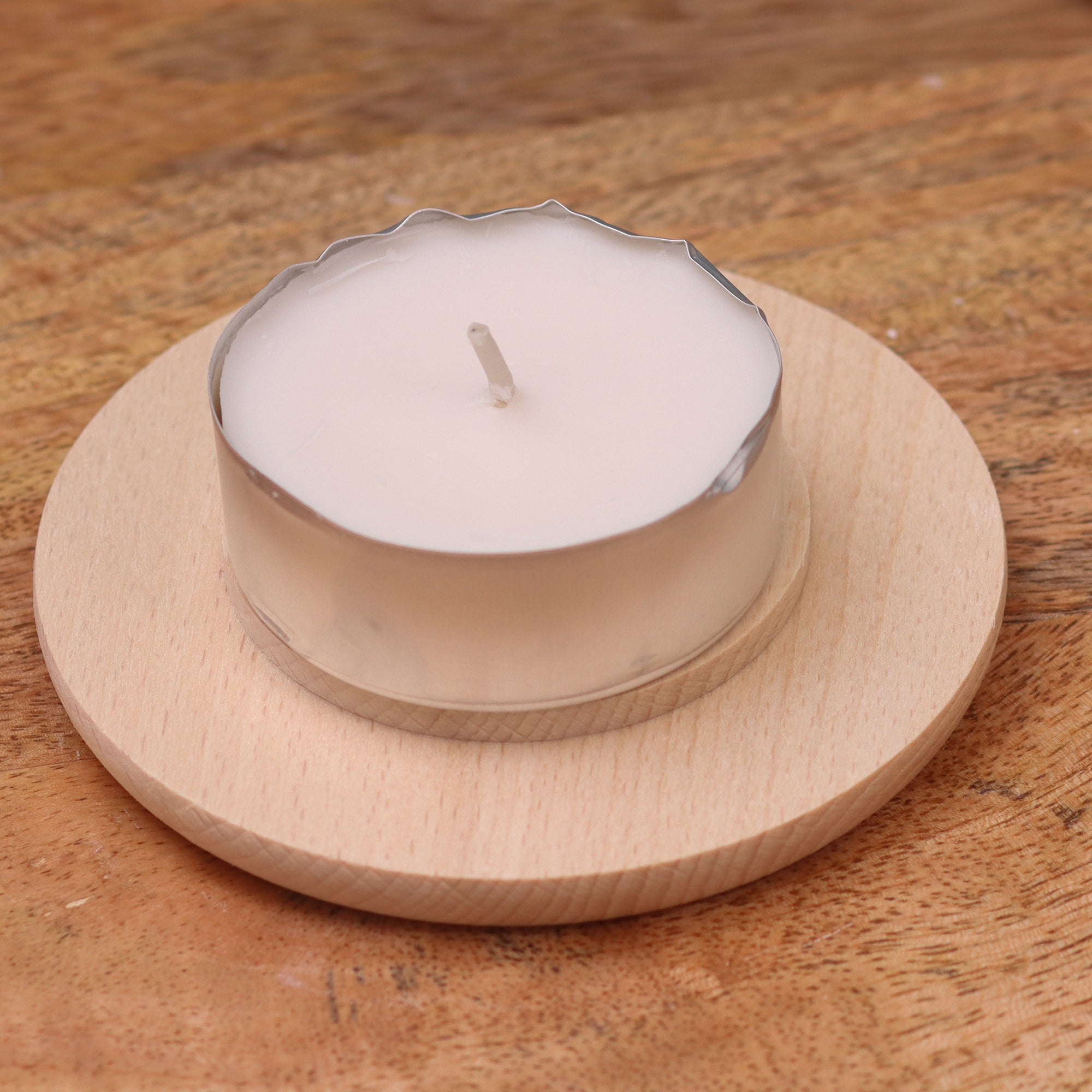 runder Holzuntersetzer mit Teelicht für Lichtkuppeln– minimalistische Produktaufnahme auf Holzfläche