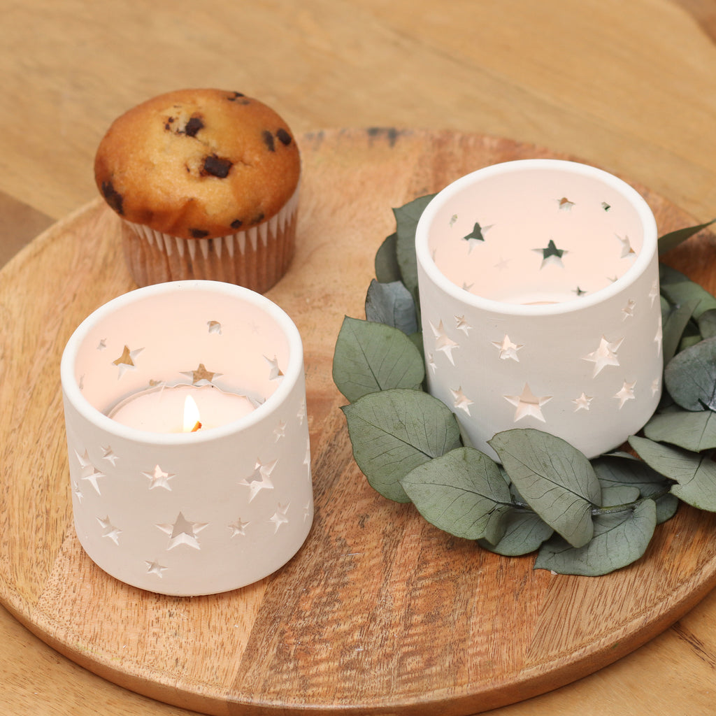 Teelicht-Windspiel-Zwei Gießobjekte aus weißem Gips mit Sternen-Design, stimmungsvolle Beleuchtung- mit Eukalyptuskranz und Muffin–auf Holztablett
