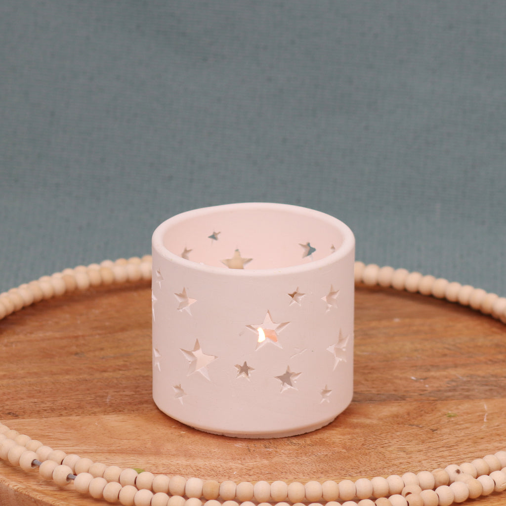 Teelicht-Windspiel-leuchtend-Gießobjekt aus weißen Gips mit Sternenausstanzungen -auf Holzplatte mit Holzperlenkranz vor türkisfarbenem Hintergrund