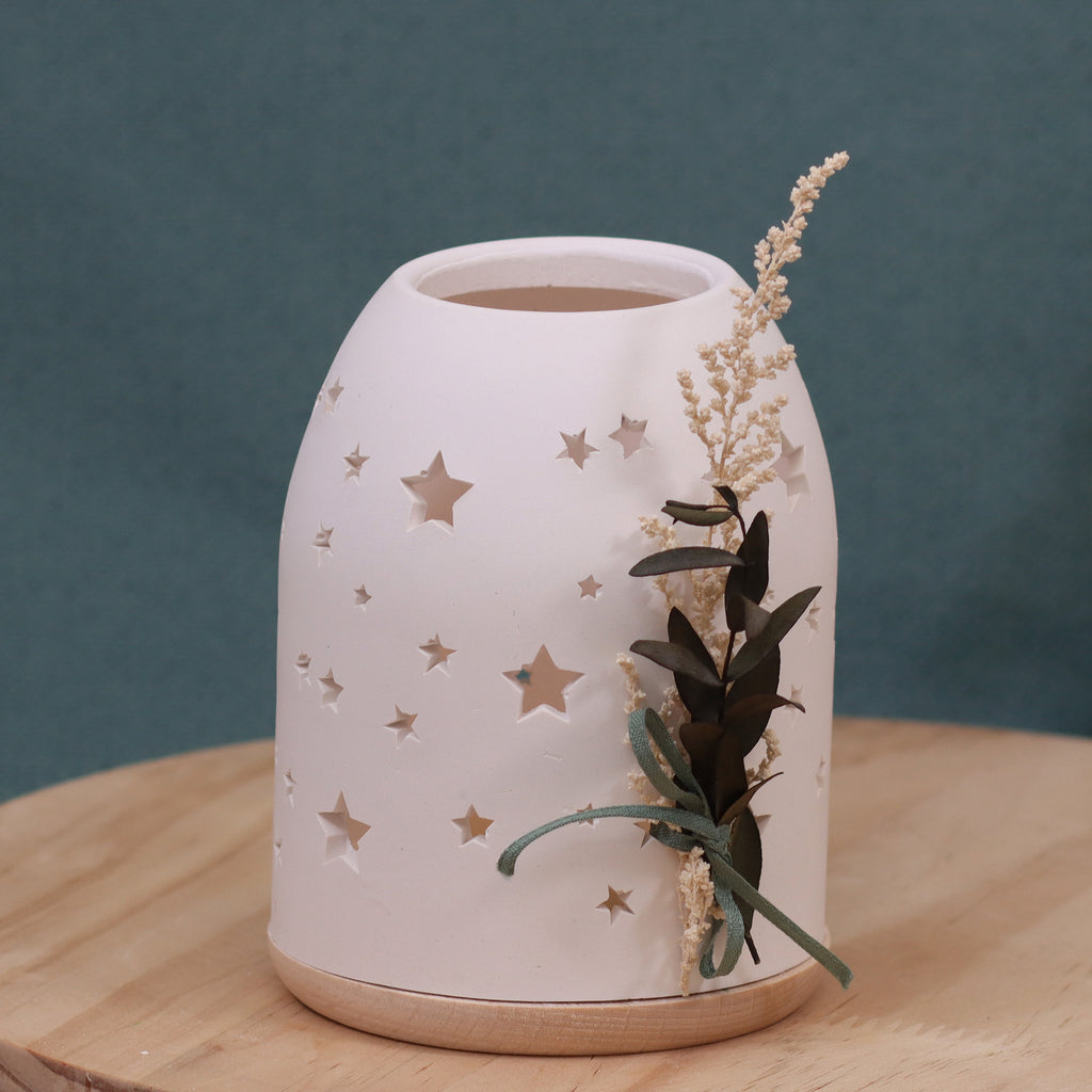 Teelicht-Lichtkuppel-gegossenes Dekoobjekt mit Sternenmuster – auf Holzplatte, mit Trockenblumen dekoriert, vor türkisfarbenem Hintergrund