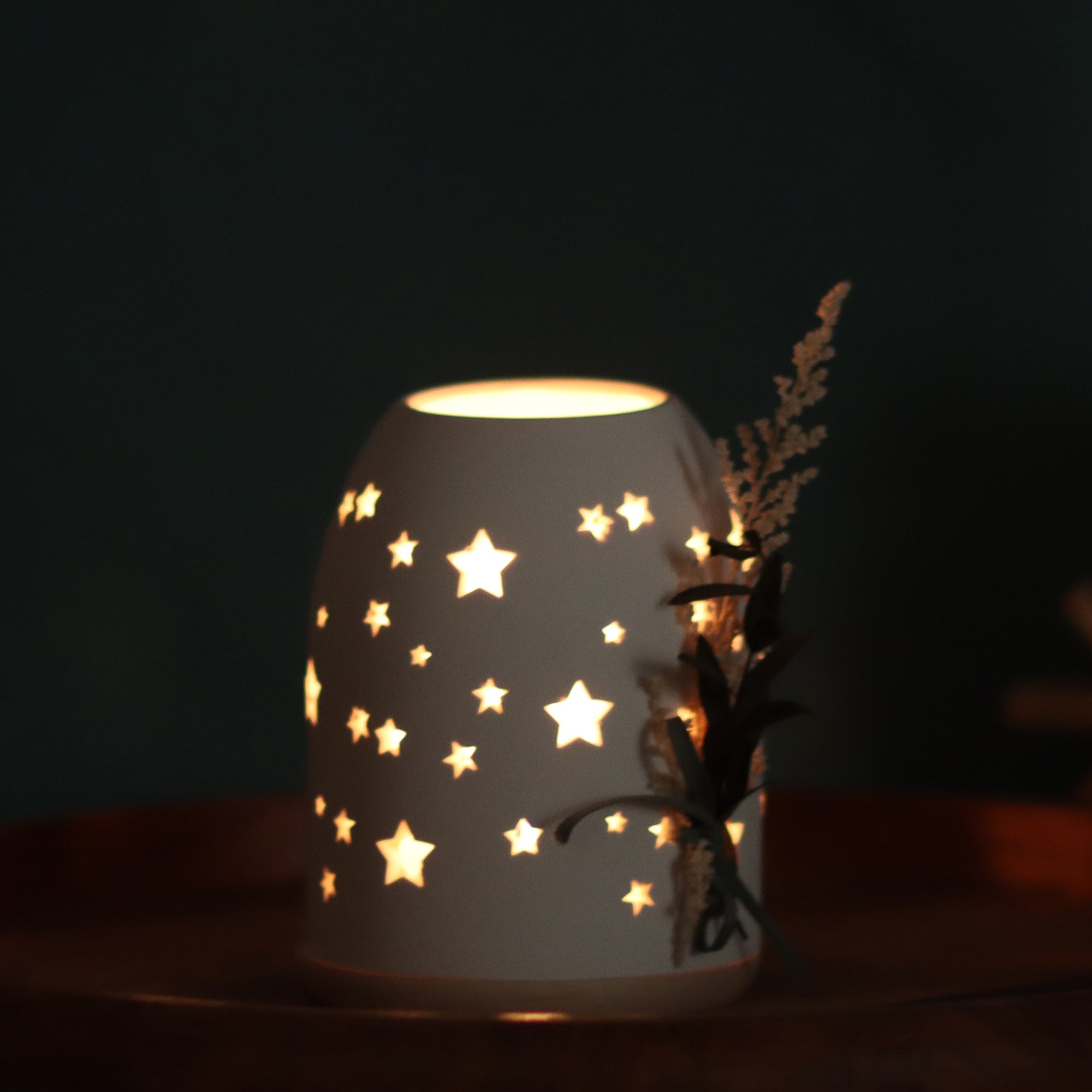 Teelicht-Lichtkuppel-beleuchtetes Dekoobjekt mit Sternenmuster – warmes Innenlicht im dunklen Setting, filigrane Sternausschnitte sichtbar